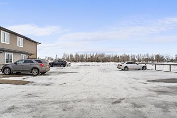 A parking lot with three cars and a building in the background.